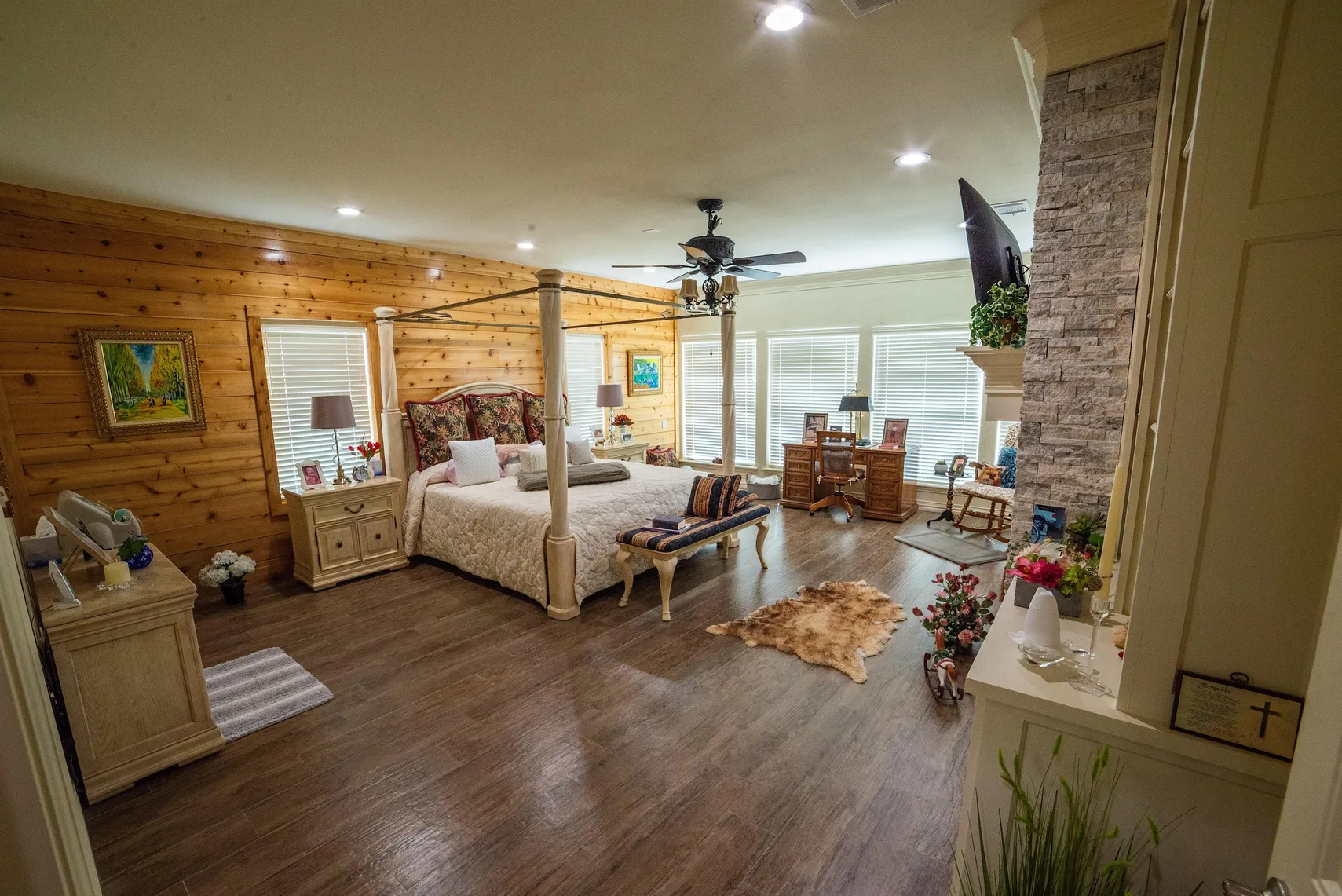 Primary suite with wood-paneled wall and stone fireplace
