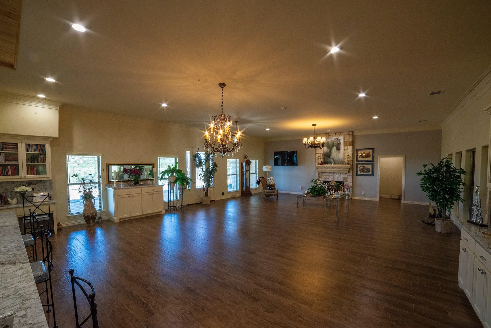 Great room with stone fireplace, chandeliers, and open floor plan